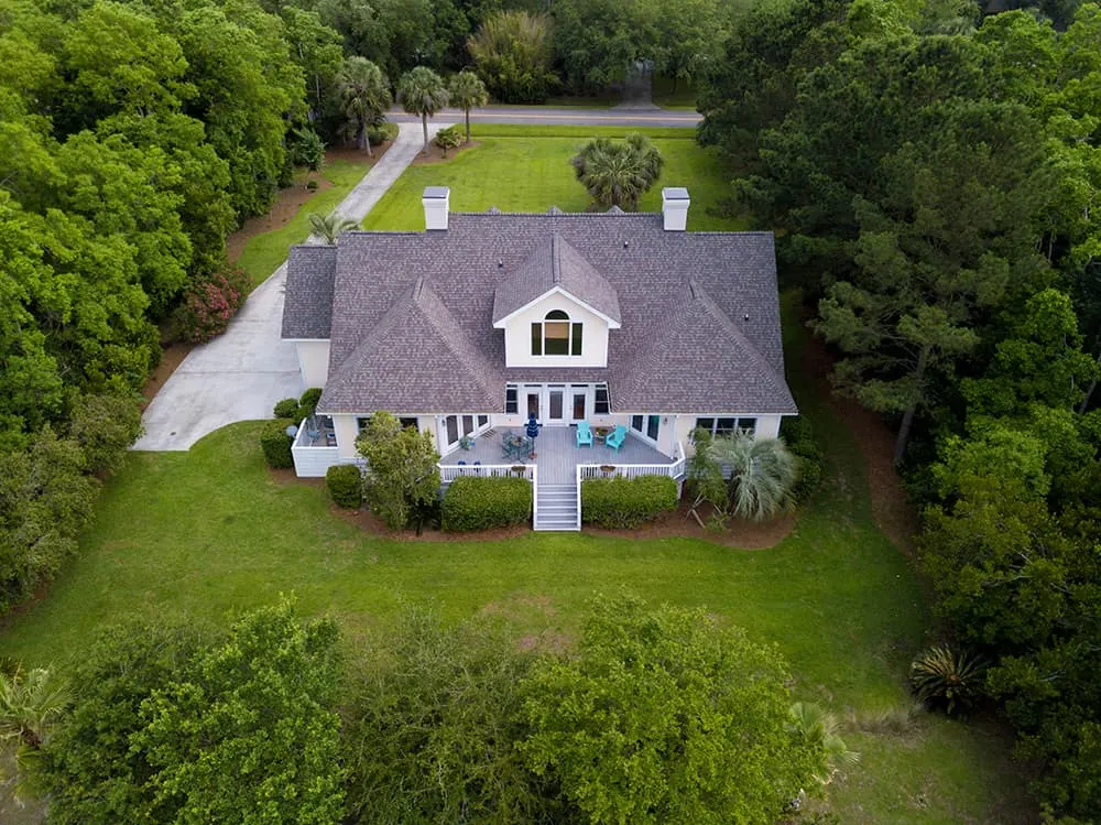 Aerial view of a large home with a new roof in the woods